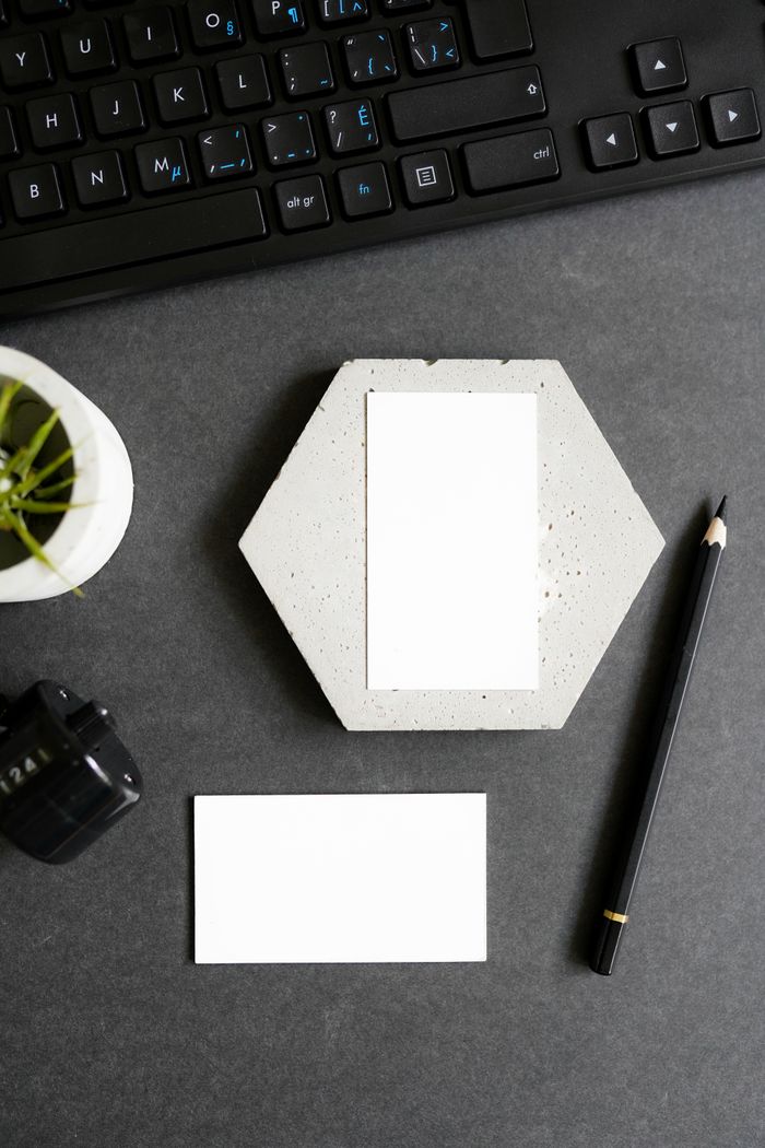 Overhead shot of business cards and stationery on a dark desk with modern accessories.